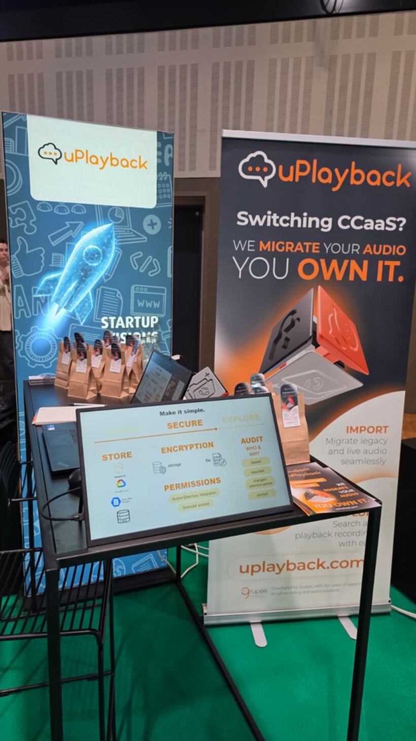 Stand da uPlayback numa conferência de tecnologia, com roll-ups, ecrã de apresentação e merchandising